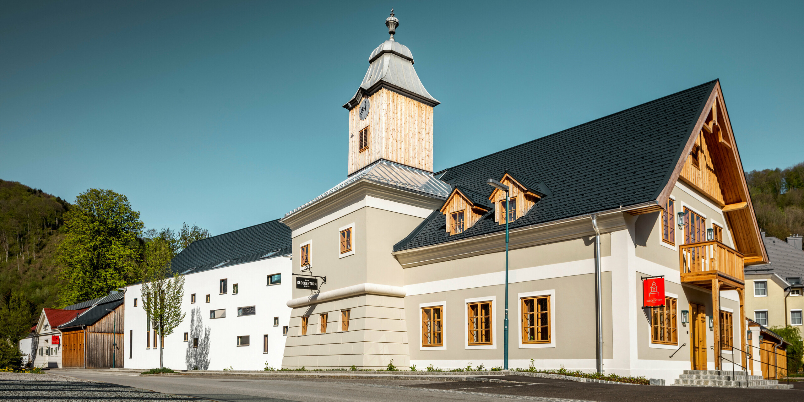 Das Dach des Hotels Glockenturm in Marktl bei Lilienfeld wurde mit der PREFA Dachschindel in P.10 Anthrazit verkleidet. Das PREFA Dachentwässerungssystem des Gebäudes ist in Naturblank gehalten. Unweit vom Hotel Glockenturm liegt das Leopold - unser Wirtshaus. Das Restaurantgebäude wurde ebenfalls mit PREFA Produkten eingedeckt.