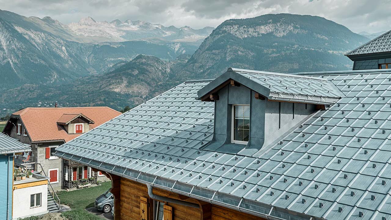 Dvostrešni krov s krovnom kućicom; na krovnoj površini položen je limeni krov tvrtke PREFA - krovna ploča u kameno sivoj. Krovna kućica obložena je kutnim stojećim falcom tvrtke PREFA u kameno sivoj.