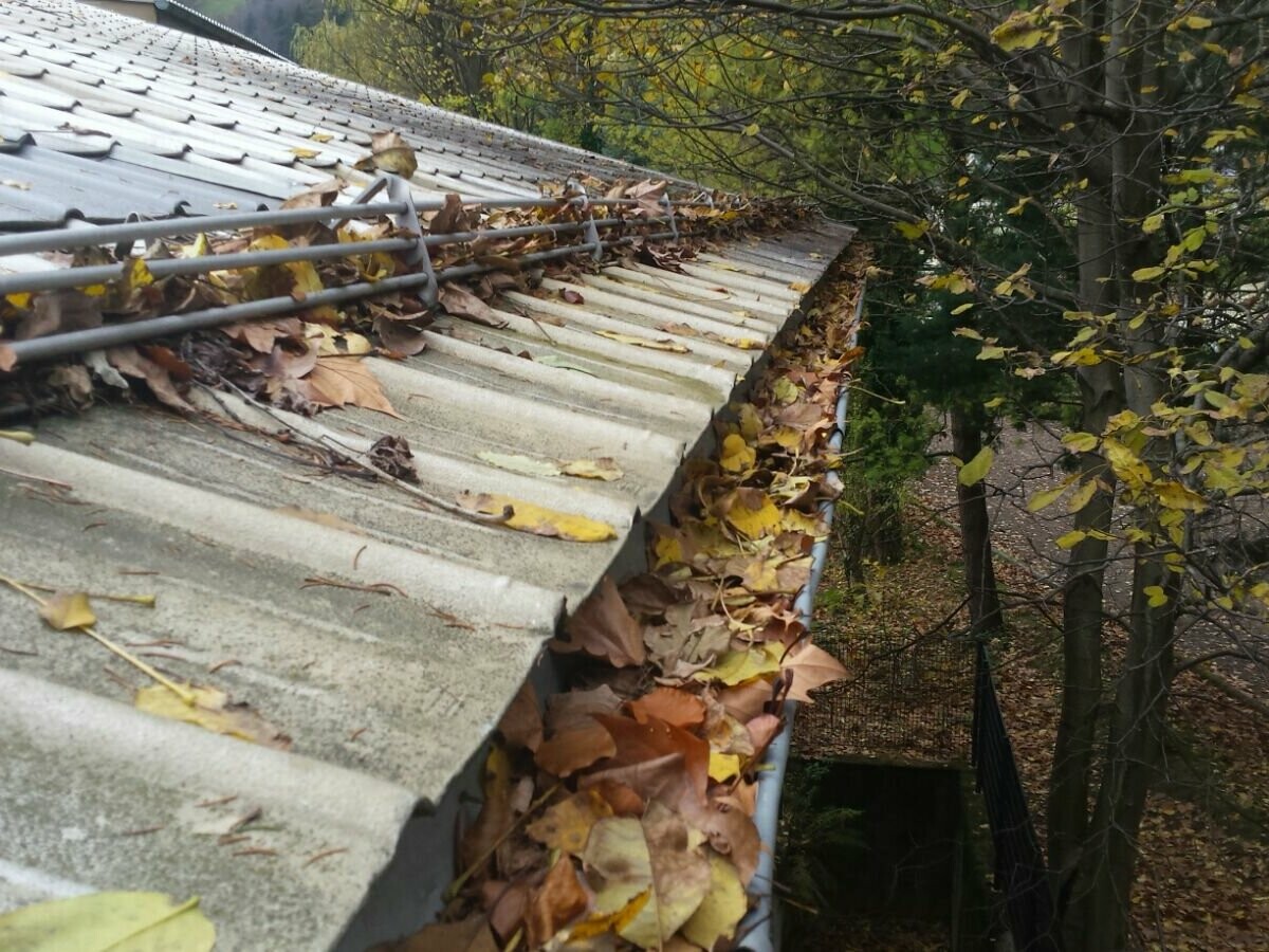 Krovni žlijeb s puno jesenskog lišća, začepljeni žljebovi koje treba očistiti