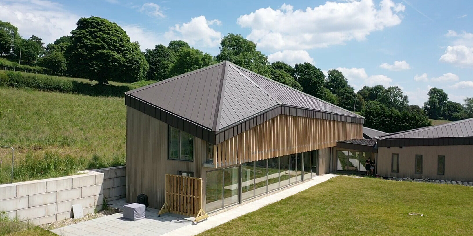 Schräge Ansicht auf ein Langhaus mit einem Stehfalzdach aus Aluminium in Braun