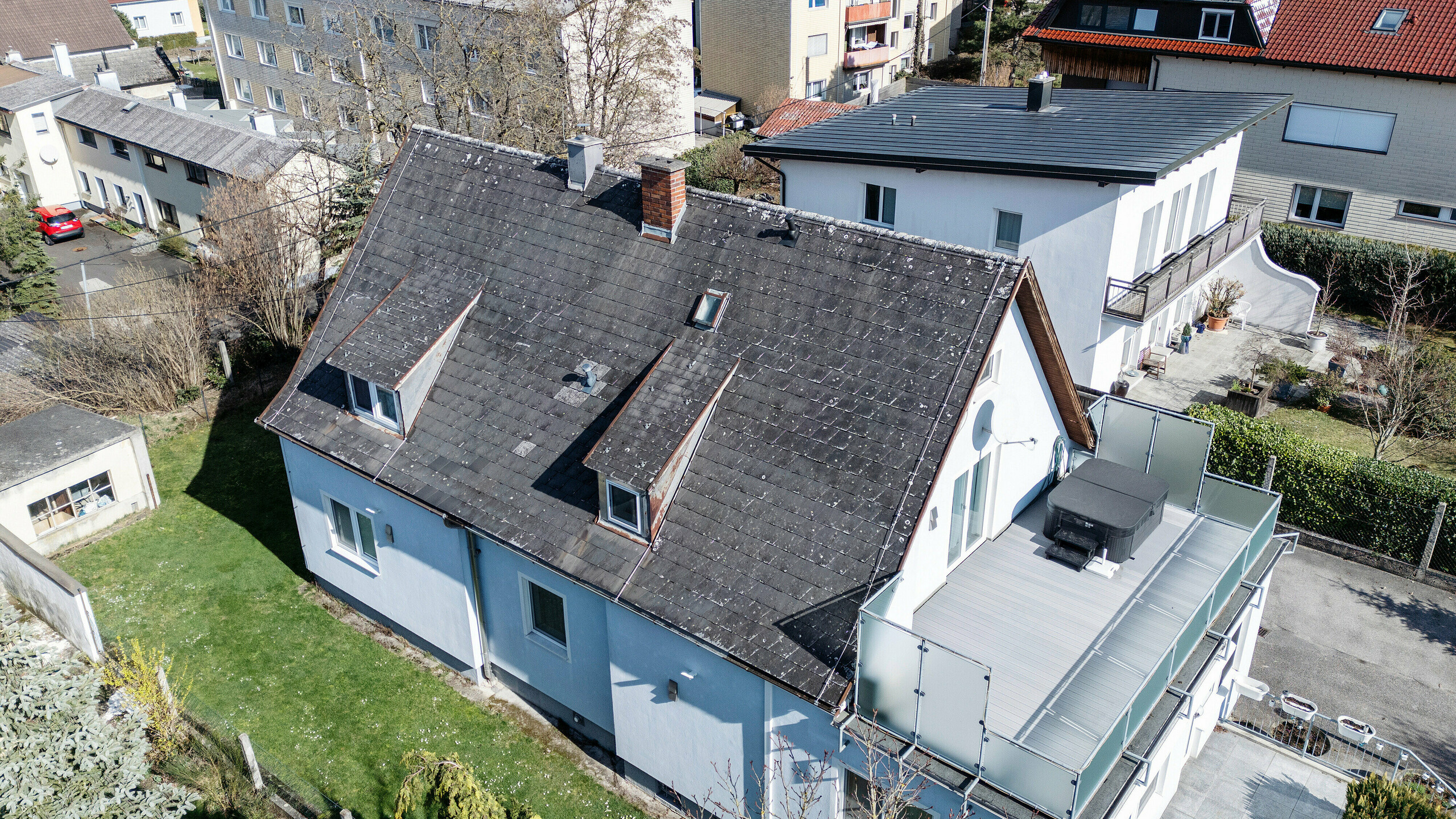 Dach eines Einfamilienhauses in Leonding vor der Sanierung mit PREFA Solardachplatten in Anthrazit. Das Bild zeigt das alte, abgenutzte Dach von Eternit aus einer seitlichen Vogelperspektive. Sichtbare Schäden und Abnutzungen unterstreichen die Notwendigkeit einer Dachsanierung und die Installation einer modernen, nachhaltigen Solaranlage. Diese Aufnahme veranschaulicht den Ausgangszustand vor der Umwandlung in eine energieeffiziente und wetterbeständige Dachkonstruktion.