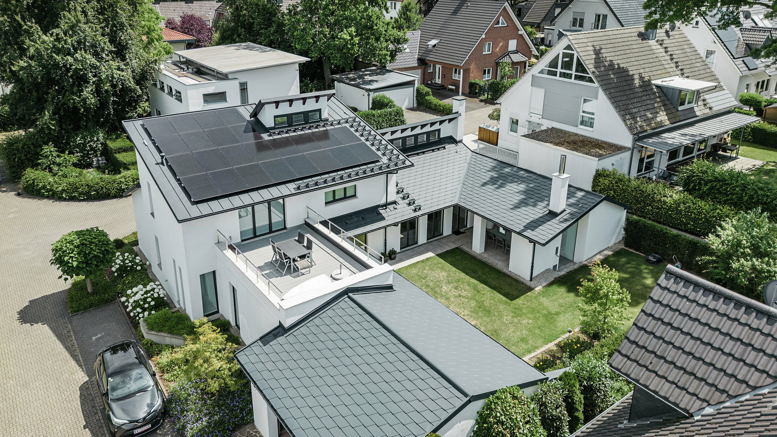  Pogled iz ptičje perspektive na izvanredan krovni krajolik obiteljske kuće u Dortmundu s PREFA krovnom šindrom DS.19 i PREFALZ u boji P.10 antracit i velikim PV sustavom