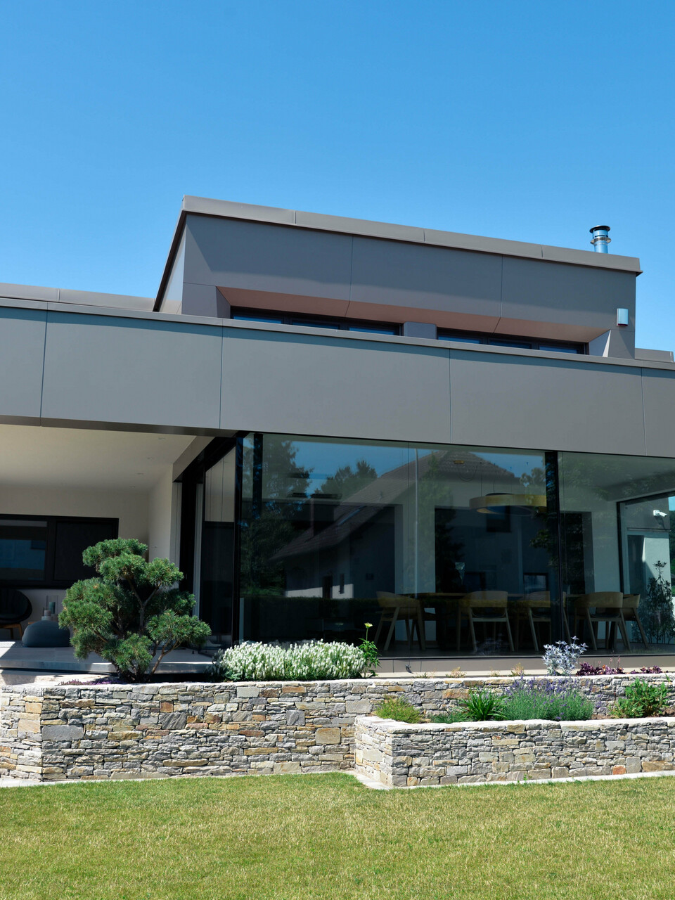 Garten und Terrasse eines Einfamilienhauses in Viehofen mit einer Gebäudehülle aus PREFA Aluminium